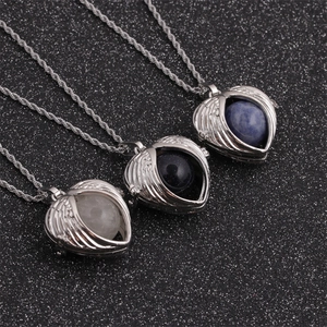 Three silver angel wing heart lockets with multi-colored gemstone spheres on a dark background