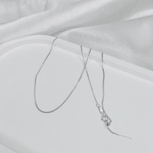 Macro detail of fine S925 sterling silver chain with adjustable spring clasp and ball charm