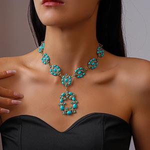 Détail d'un collier vintage doré avec des pierres turquoise et un design ajouré