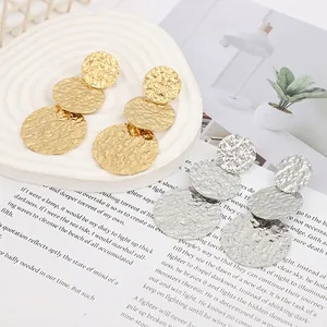 Detailed macro view of bohemian triple disc drop earrings with textured hammered finish