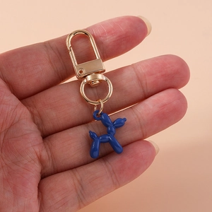 Close-up of bright blue balloon dog keychain with golden lobster clasp held in hand