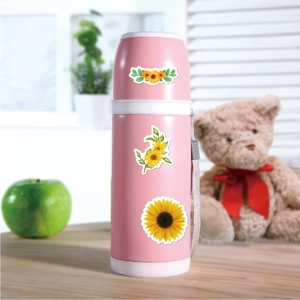 Pink insulated water bottle with cute sunflower decals on a cozy wooden desk setting