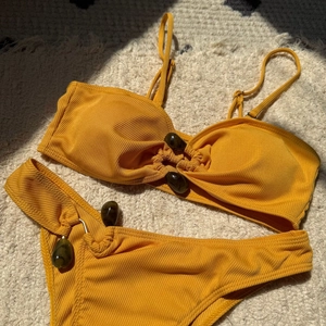 Detail view of bright yellow ribbed bikini set with decorative stones on textured fabric