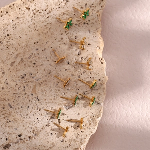 Macro detail of gold plated flower stud earrings with green and white zircons