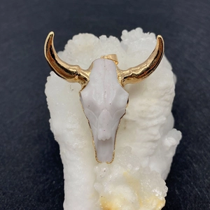 White bull skull pendant with gold horns on a white crystal cluster background