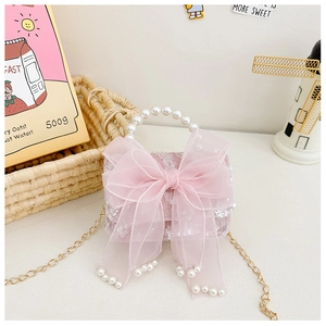 Detailed macro of pink sequin girls bag with lace bow and pearl handle with gold chain