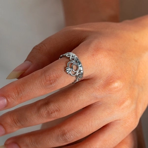 Detailansicht eines silbernen Kronenrings im Claddagh-Stil an einem Finger, poliertes Finish