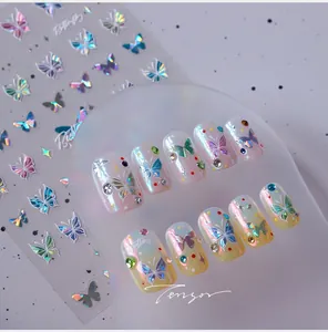 Detailed view of holographic butterfly nail stickers with 3D crystal and bead embellishments