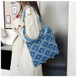 Detail of denim tote bag with 3D star patchwork and fringe on model shoulder