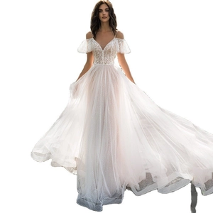 Detail of white bridal gown featuring intricate lace embroidery and ruffled off-shoulder sleeves