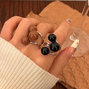 Three-bead open ring with enamel spheres in brown and black forming a cartoon silhouette