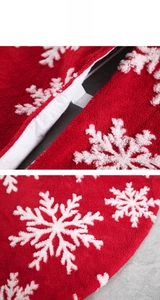 Detail of red plush Christmas tree skirt featuring white snowflake patterns and velcro