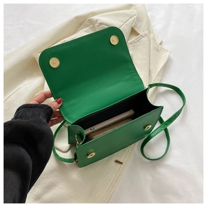 Detail view of green PU leather crossbody bag with golden magnetic clasp and interior space