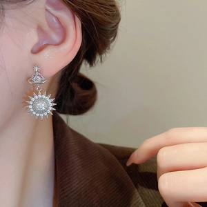 Detail of silver Saturn and star earrings with zircon crystals on model's ear