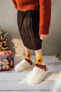 Detail showing plush white slippers and reindeer patterned Christmas socks in warm cozy setting