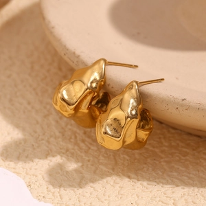 Macro shot of 18K gold plated earrings with irregular lava texture and hammered finish