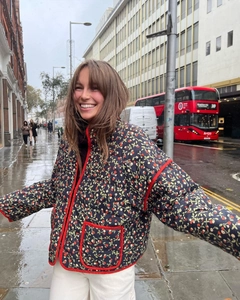 Detail of floral quilted cotton jacket with red contrast piping on a London street