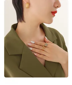Detailed shot of gold grid earrings and dalmatian stone ring on fashion model