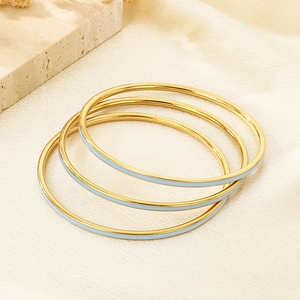 Macro shot of three stacked gold-plated bangles with light blue enamel inlay detailing