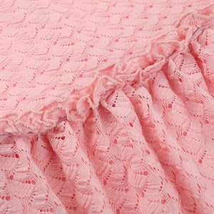 Gros plan sur un tissu en dentelle rose avec des motifs floraux et des volants délicats