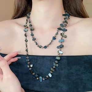 Detail view of double-layered beaded necklace with irregular shell and faceted glass beads