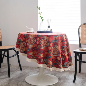 Bohemian round tablecloth with red geometric patterns and beige fringed edges on a table