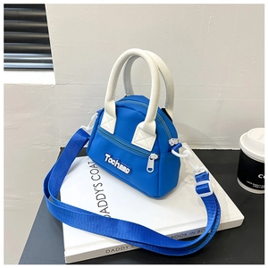 Detail of blue mini kids handbag with white contrast handle and wide crossbody strap