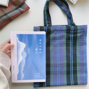 Nahaufnahme der blau-grünen Vintage-Canvas-Tasche mit Karomuster auf Holztisch