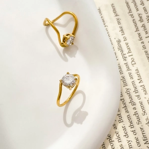 Detail of two gold curved rings with round cubic zirconia on white ceramic tray