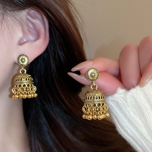 Close-up of golden vintage Jhumka earrings with intricate hollow patterns and beads