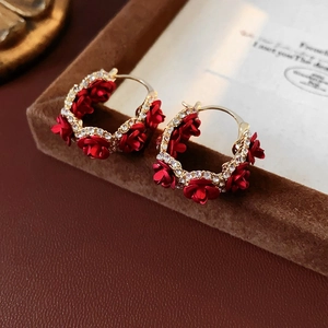 Detail view of gold-plated red rose earrings with sparkling rhinestone floral accents