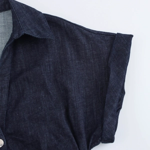 Dettaglio ravvicinato del colletto e dei bottoni dorati sul tessuto dell'abito in denim