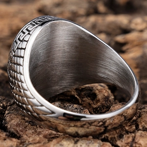 Macro shot of vintage steel ring featuring Greek meander patterns and scale textures