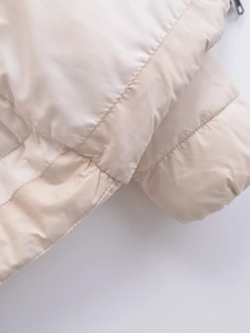 Detailed close-up of cream white padded jacket featuring quilted stitching and premium texture