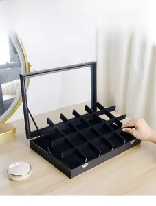 Detalle de joyero negro con tapa de vidrio y compartimentos de terciopelo ajustables