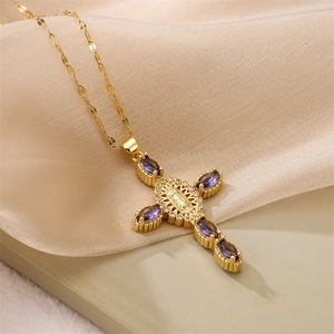Détail du pendentif croix dorée avec vierge marie et zircons violets sur du satin