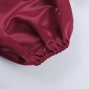 Détail de la manche d'une robe en satin bordeaux avec poignet élastique et tissu lisse