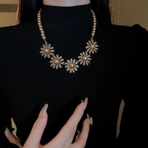 Detail of flower necklace with champagne pearls on black turtleneck backdrop