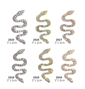 Detailed view of six 3D snake nail charms in gold and silver with sparkling rhinestones