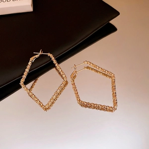 Detail view of gold geometric rhombus earrings with fine wire-wrapped pleated texture