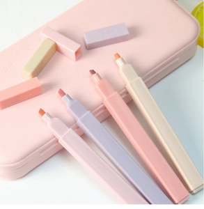 Close-up of four macaron-colored square highlighters with chisel tips in a pink storage case