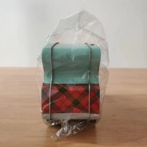 Detailed view of car-shaped Christmas tin box in plastic wrap on a wooden table