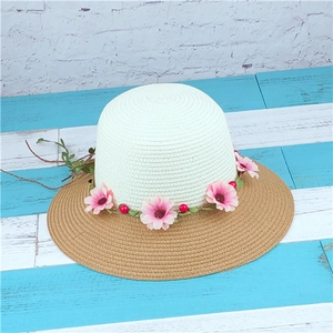 Detail of woven sun hat featuring a floral wreath with pink daisies and green leaves