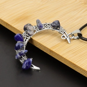 Macro shot of a silver wire-wrapped crescent moon pendant with blue crystal stones