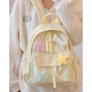 Close-up of minimalist cream backpack featuring colorful star plush charms and soft fabric