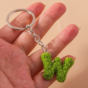 Detail of green letter W keychain with floral rose texture and silver metal ring