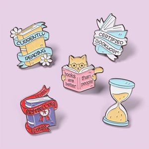 Detailed view of enamel pins set featuring books, cats and a sandglass on purple background
