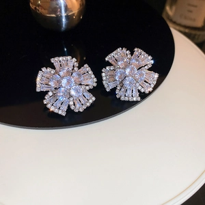 Close-up of flower stud earrings with sparkling cubic zirconia on a reflective surface