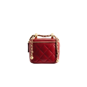 Detailed macro of red quilted leather mini vanity bag with gold chain and metal ball
