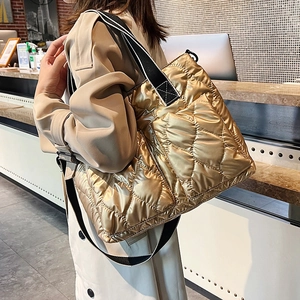 Detail of golden quilted down tote bag featuring stylish black and white striped strap